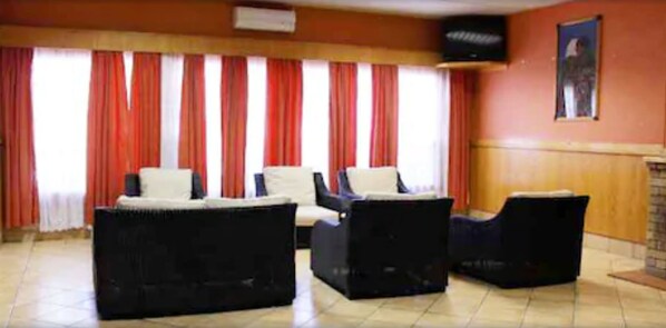 A room with a sofa set, a television mounted on the wall, and a painting. - Blue Mountain Inn (Teyateyaneng)