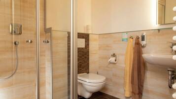 Ein modernes Badezimmer mit Duschkabine aus Glas, Toilette und Waschbecken.