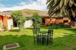 Un patio con una mesa, sillas, una palmera y un edificio de techo rojo.