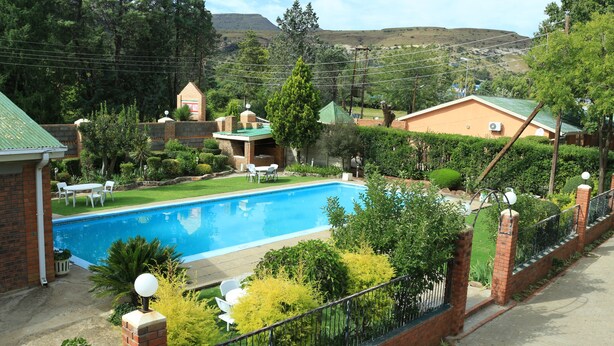 Ett bostadsområde med en swimmingpool, hus byggda av tegel och en inhägnad trädgård.