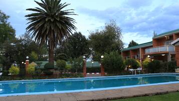 Relax by the rectangular pool surrounded by lush greenery and palm trees.