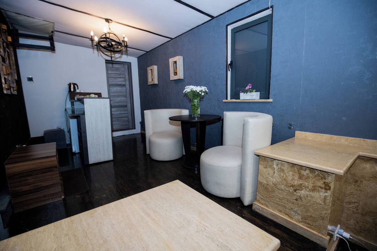 Un salon moderne avec un mur d’accent bleu foncé, une table ronde avec des chaises, une table basse en bois et un banc intégré.