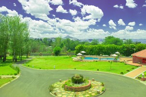 Zona ajardinada con piscina, fuente y un edificio de techo rojo.