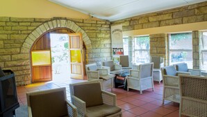 A room with stone walls, wicker furniture, and a fireplace. - Mountain View Hotel (Hlotse)