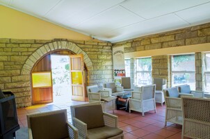 Una habitación con paredes de piedra, muebles de mimbre y una chimenea.