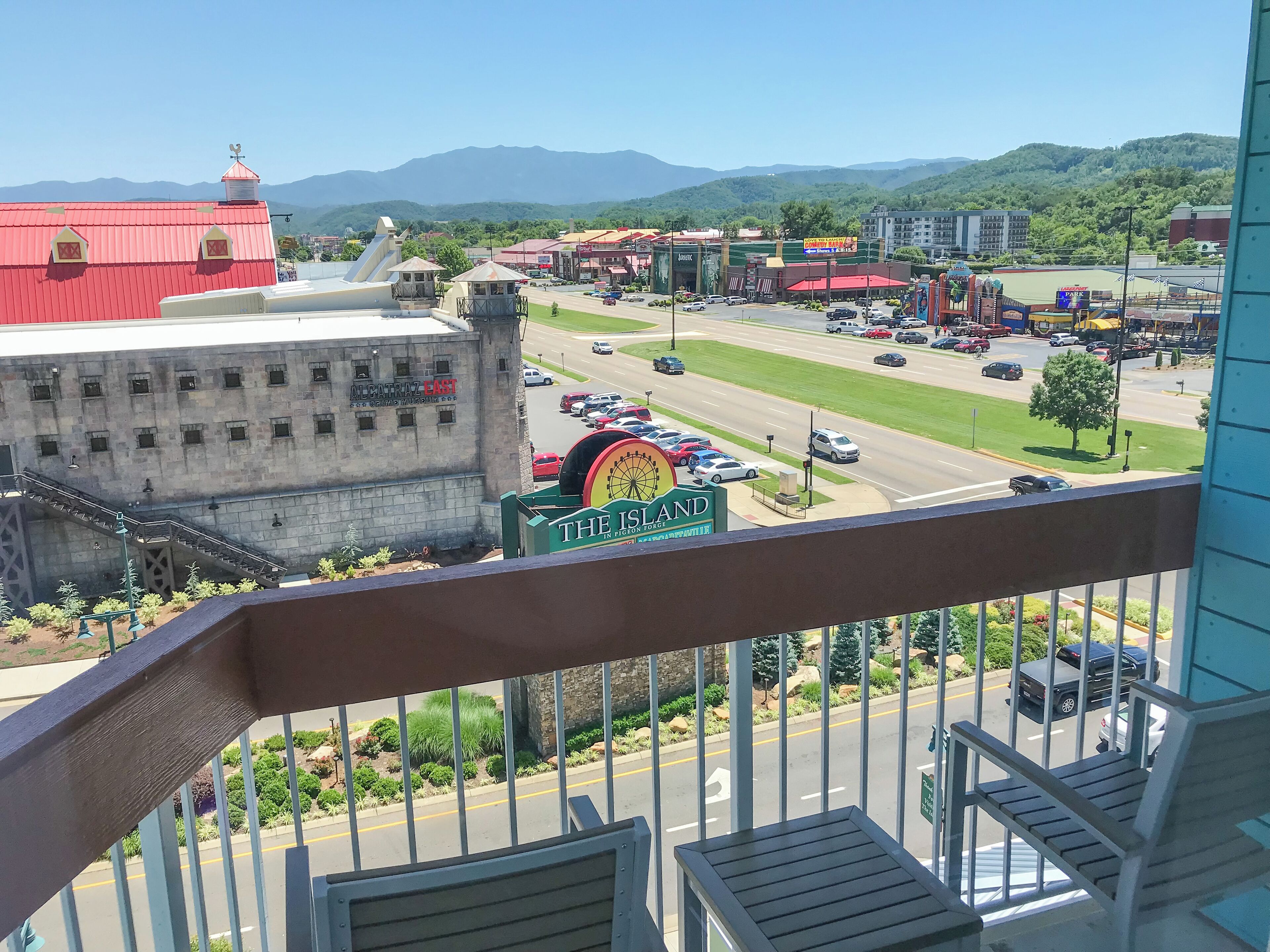 A view from a balcony overlooking a parking lot with a Ferris wheel, a red building, and a sign for "The Island in Forgo".