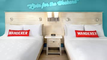 A hotel room with two beds, each with a 'Wanderer' pillow, a small bedside table with a clock, and a neon sign above reading "Win for the Weekend".