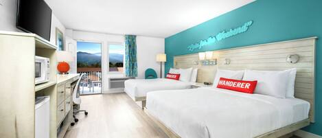 A hotel room with two beds, a TV, a desk with a lamp, and a view of mountains.
