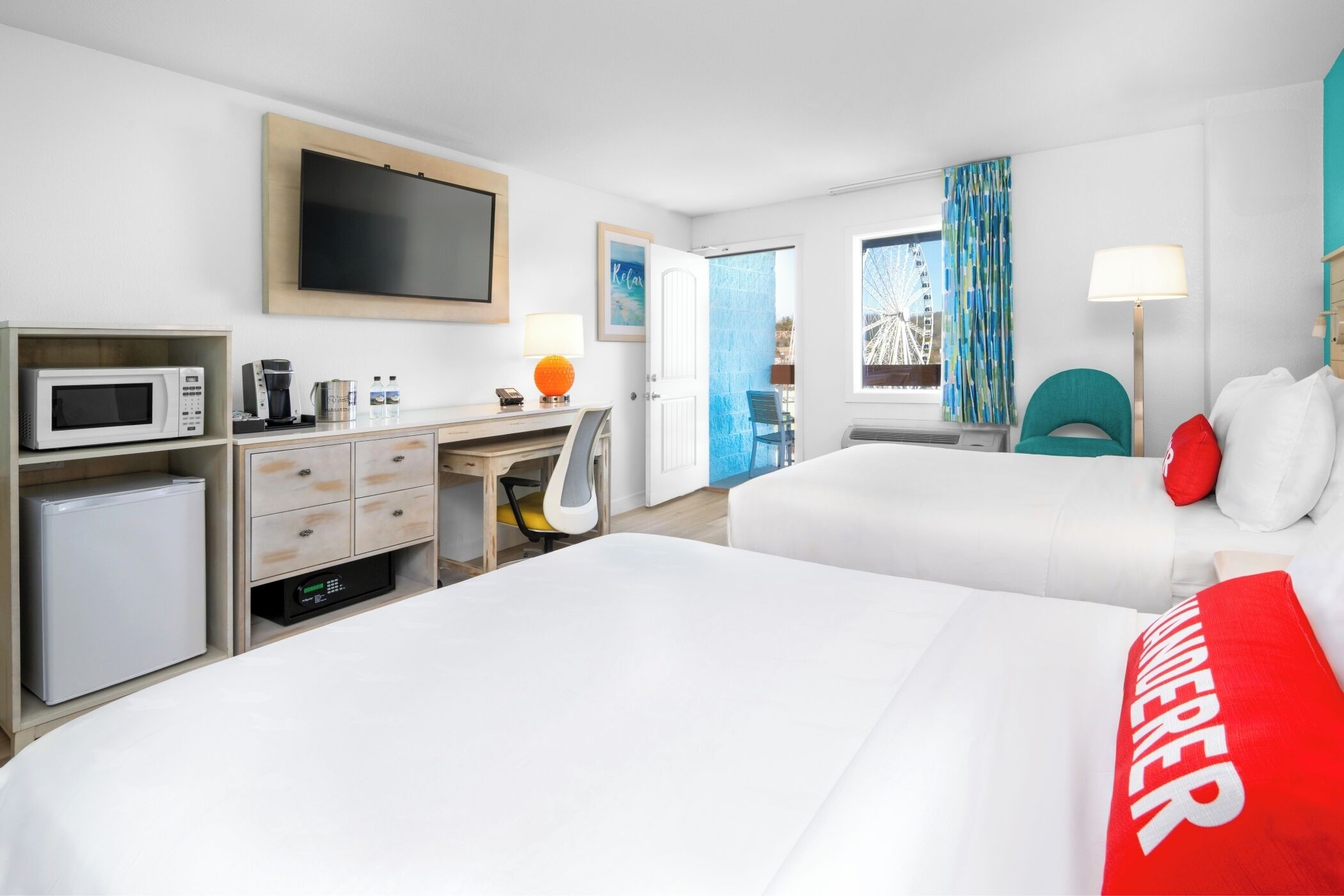 A hotel room with two beds, a desk with a computer, a microwave, and a coffee maker.