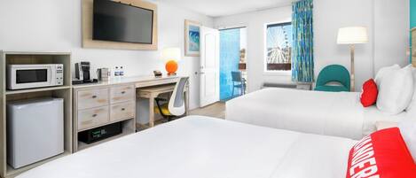 A hotel room with two beds, a desk with a computer, a microwave, and a coffee maker.