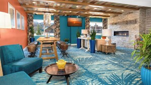 Un salon moderne avec un canapé bleu, une table en bois surmontée d’un vase jaune et une cheminée.