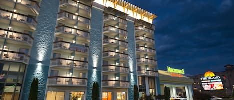 Een hotel met meerdere verdiepingen, voorzien van balkons, een zwembad en een bord met de tekst 'The Island' restaurant.