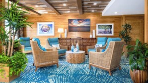 A lobby with wicker furniture, a wooden reception desk, and a blue patterned carpet. - Margaritaville Island Inn (Pigeon Forge)