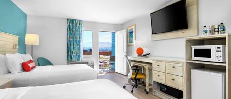 A hotel room with two beds, a desk with a computer, a TV, a microwave, and a mini-fridge.