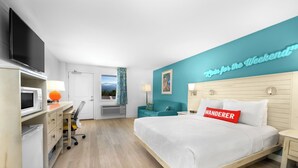Une chambre d’hôtel moderne équipée d’un lit, d’un bureau, d’une télévision et offrant une vue sur l’extérieur.
