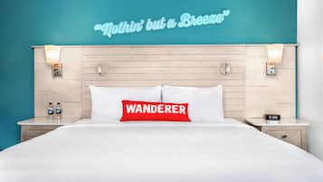 A hotel room with a bed, a wall-mounted sign, a nightstand, a bedside table, and a wall clock.