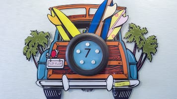 A colorful vehicle with surfboards, a clock, and palm trees.