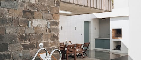 Una piscina con cubierta de madera, un muro de piedra y un área de comedor con sillas y una mesa.