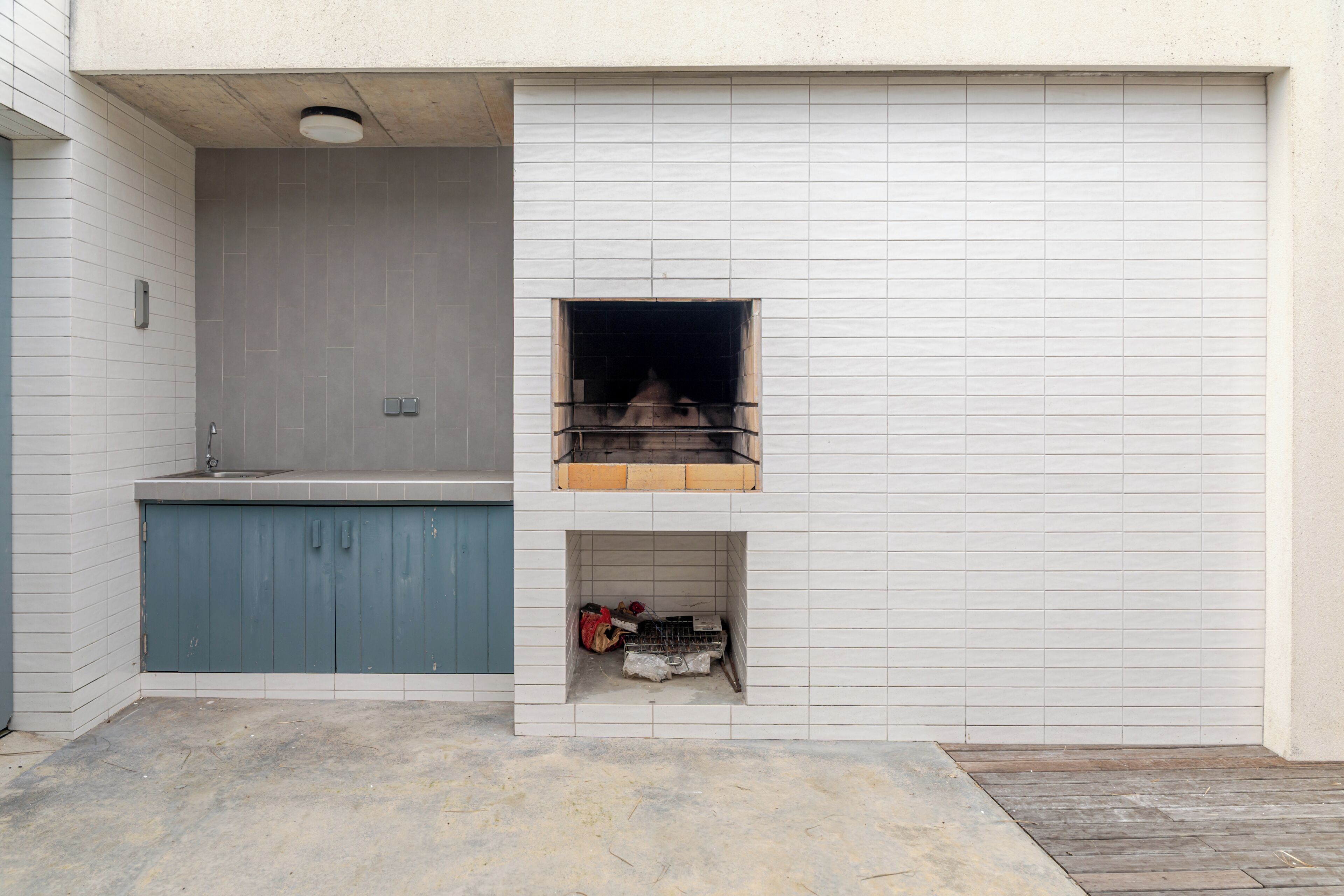 A small kitchen with a sink, a blue cabinet, and a built-in grill.