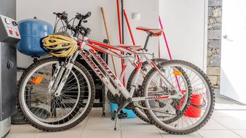 A bicycle with a helmet, a blue water heater, and a red broom leaning against a wall.