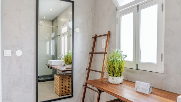 Ein Badezimmer mit Spiegel, einer Holzleiter, Topfpflanzen, einem weißen Waschbecken und einem Fenster.