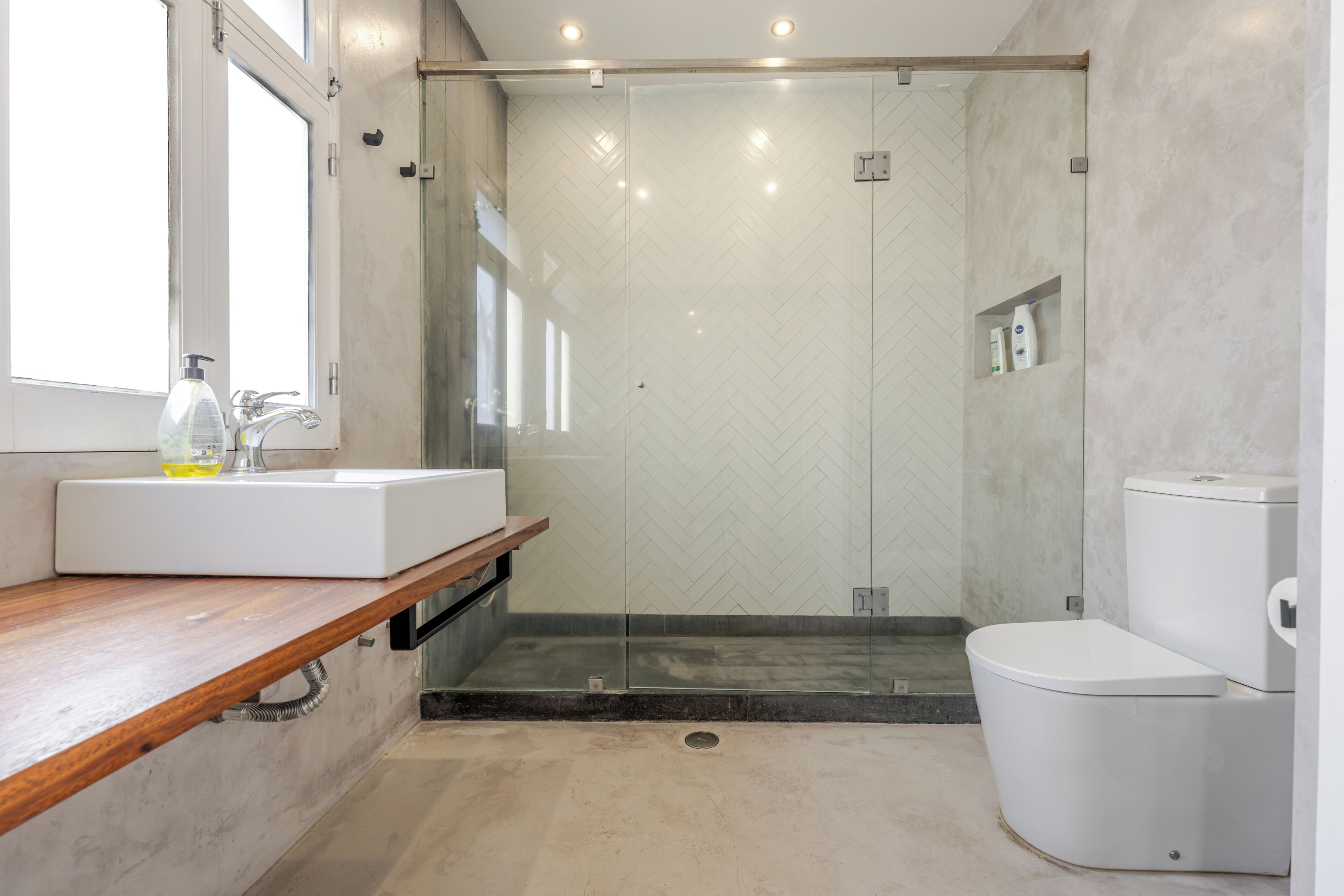 Ein modernes Badezimmer mit einem Holzkosmetikschrank, einer Duschkabine und einer weißen Toilette.