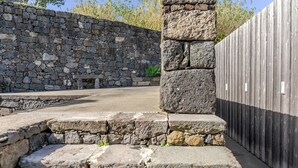 Eine Steinsäule, ein Holzzaun und eine Bank in einer Außenanlage.