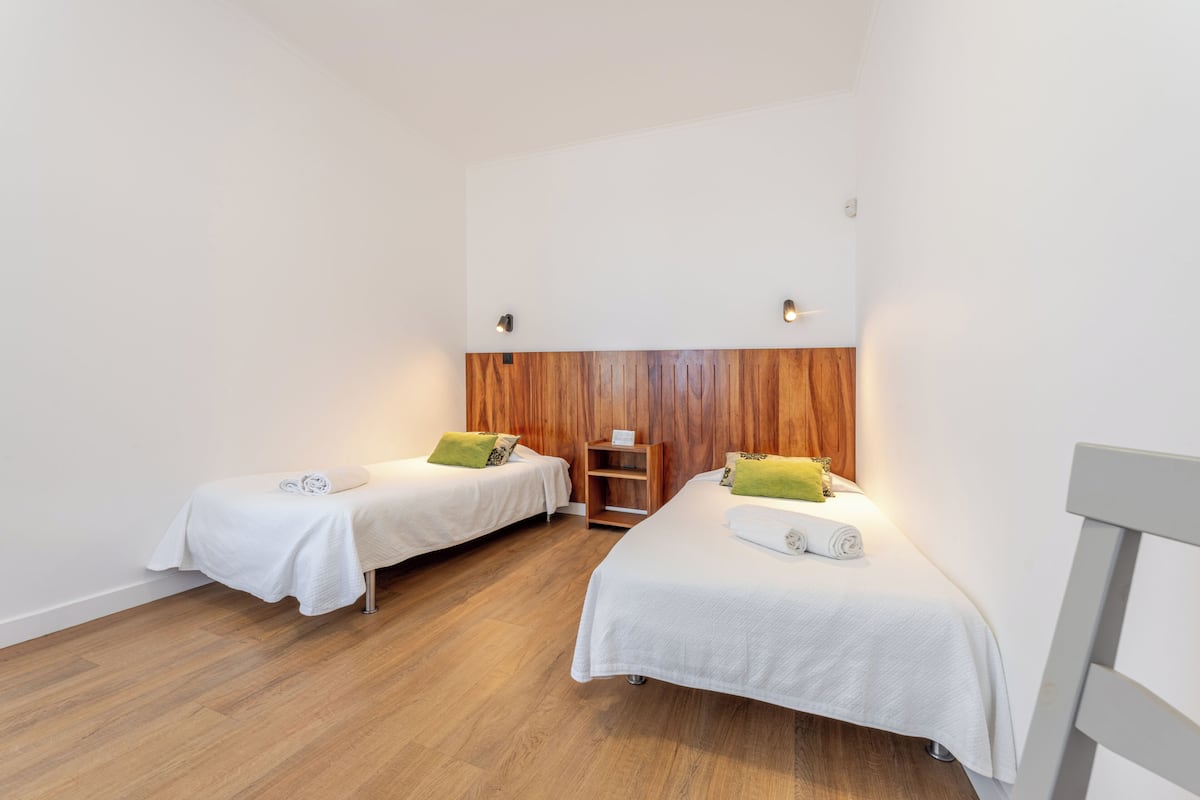 Una habitación con dos camas individuales, paneles de madera en la pared y un techo blanco.