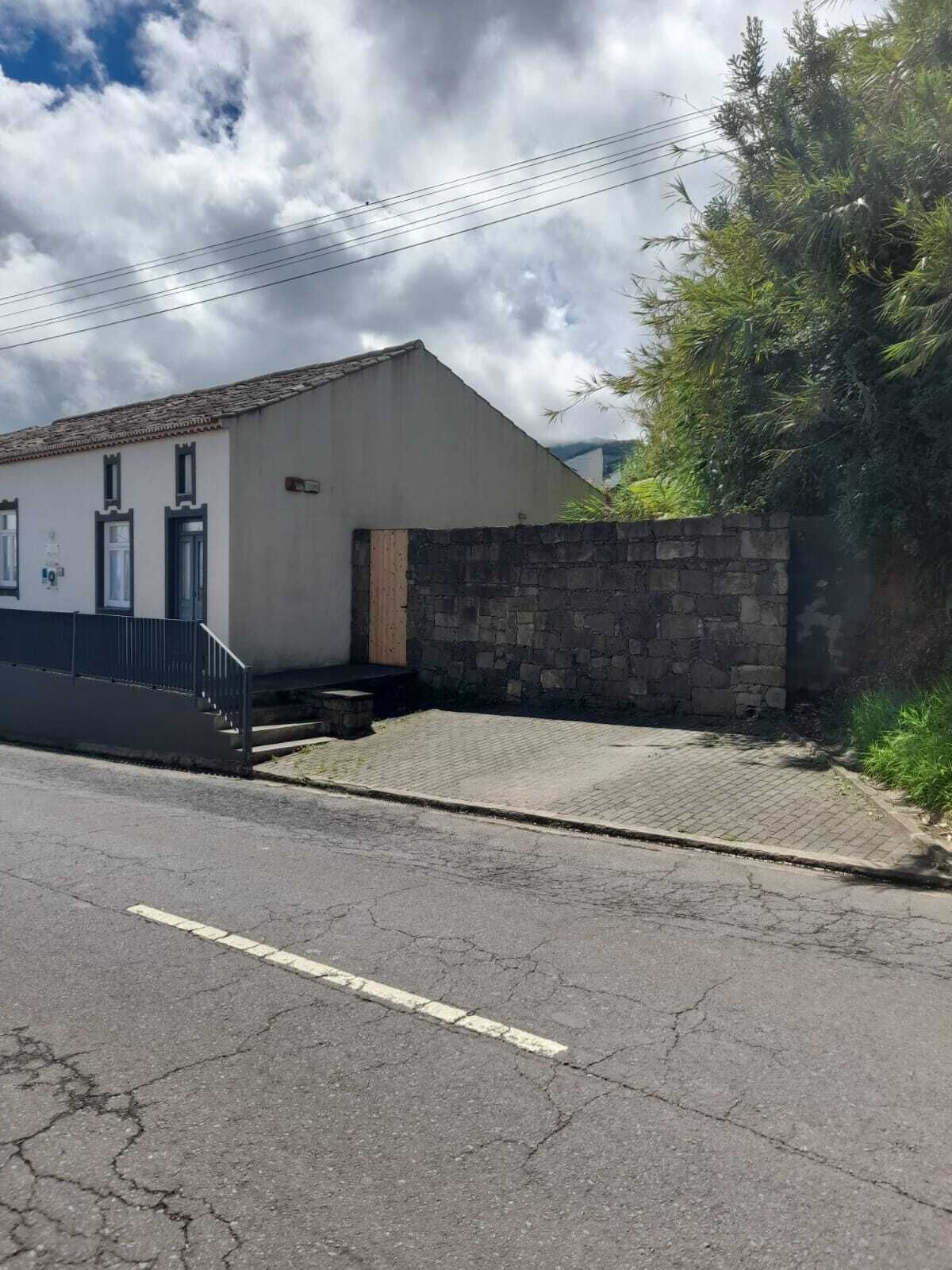 Un edificio con muro de piedra, camino pavimentado y cielo despejado.