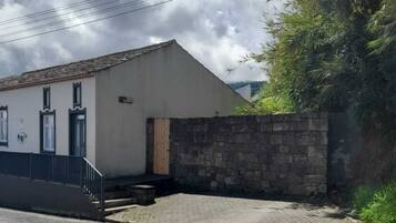 Un edificio con muro de piedra, camino pavimentado y cielo despejado.