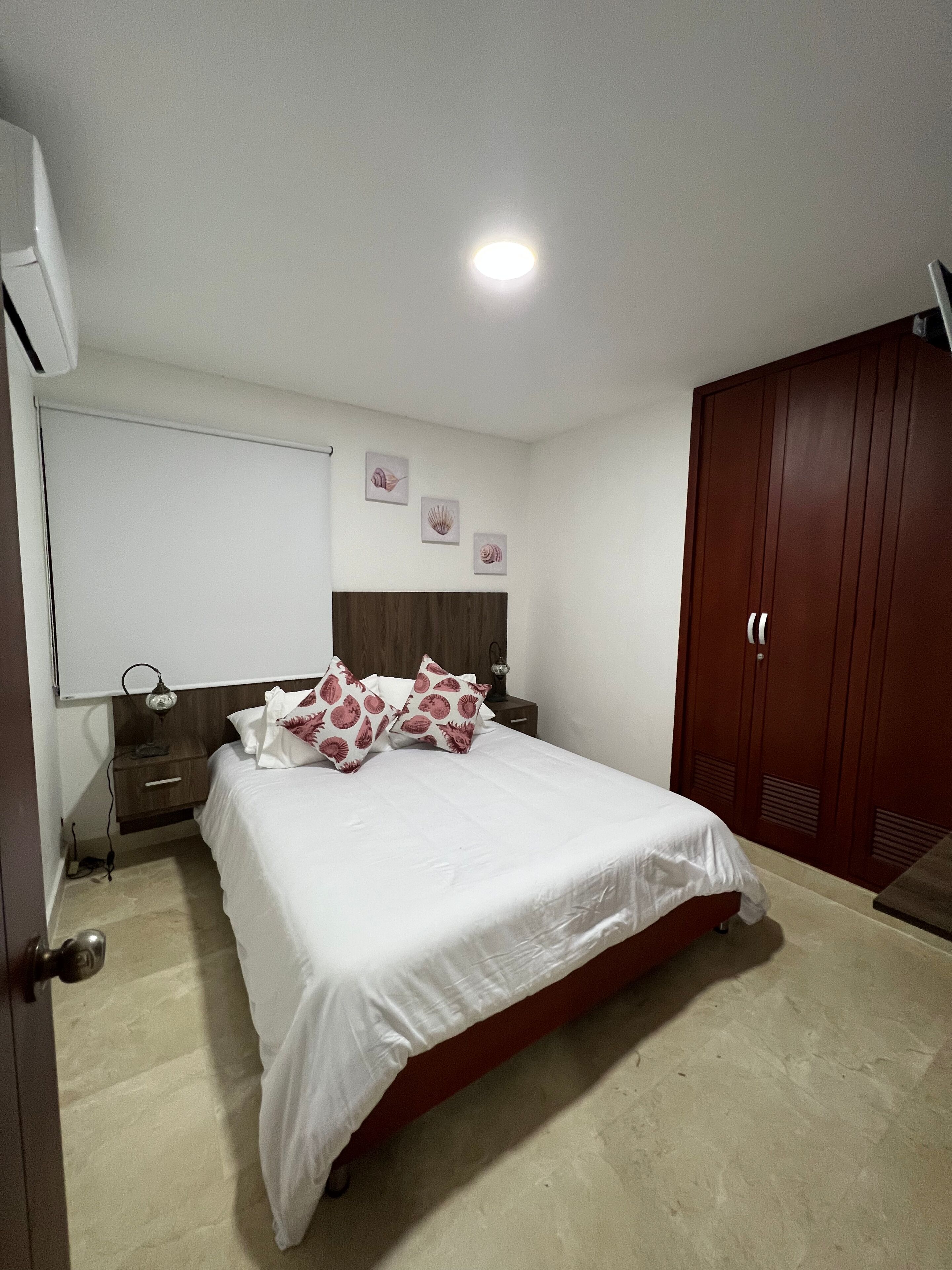 A bedroom with a bed, a nightstand, a wardrobe, and wall art.