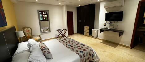 A hotel room with a bed, a desk, a chair, a TV, and a wardrobe.