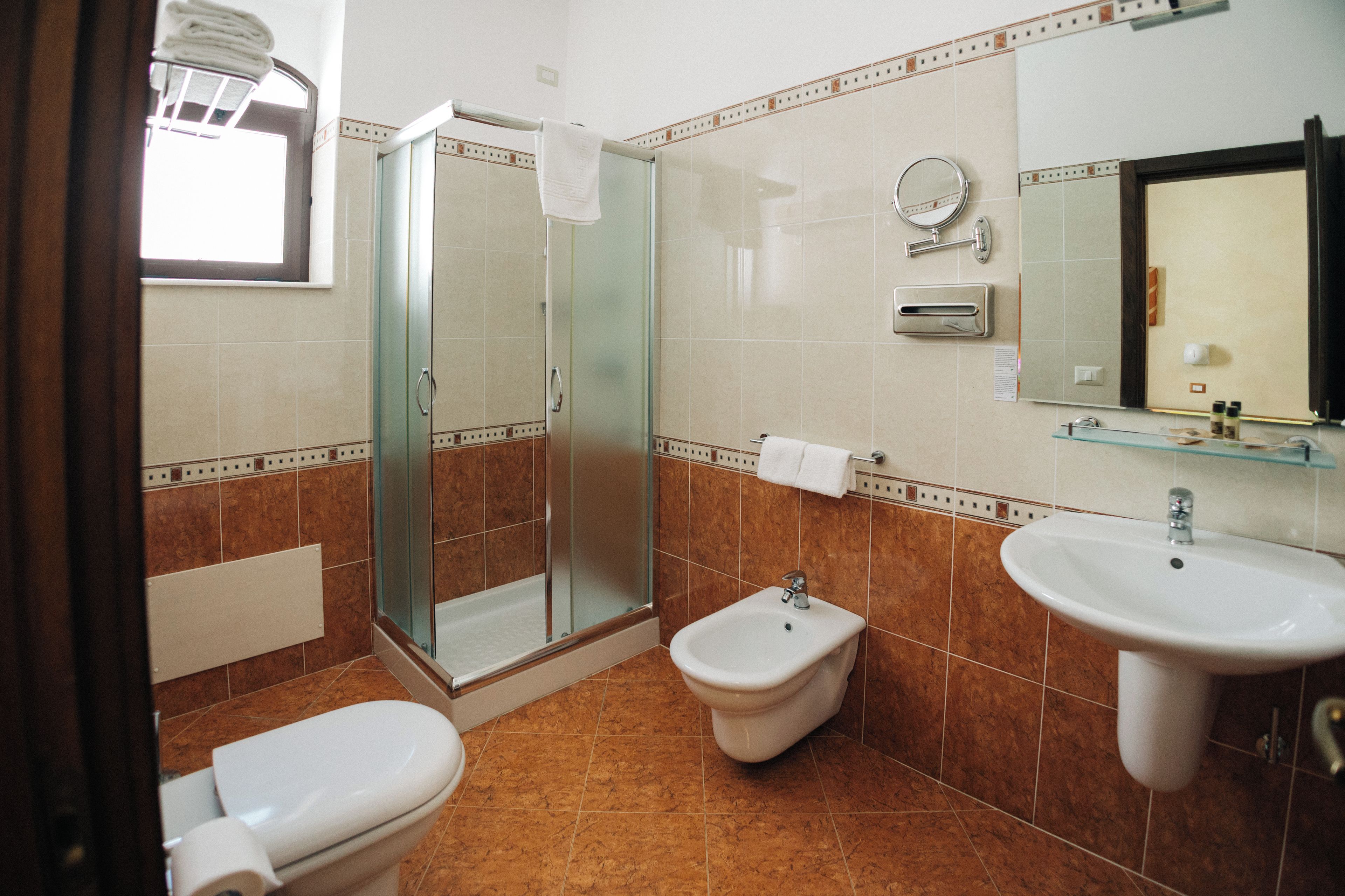 A bathroom with a glass-enclosed shower, a bidet, a sink, and a toilet.