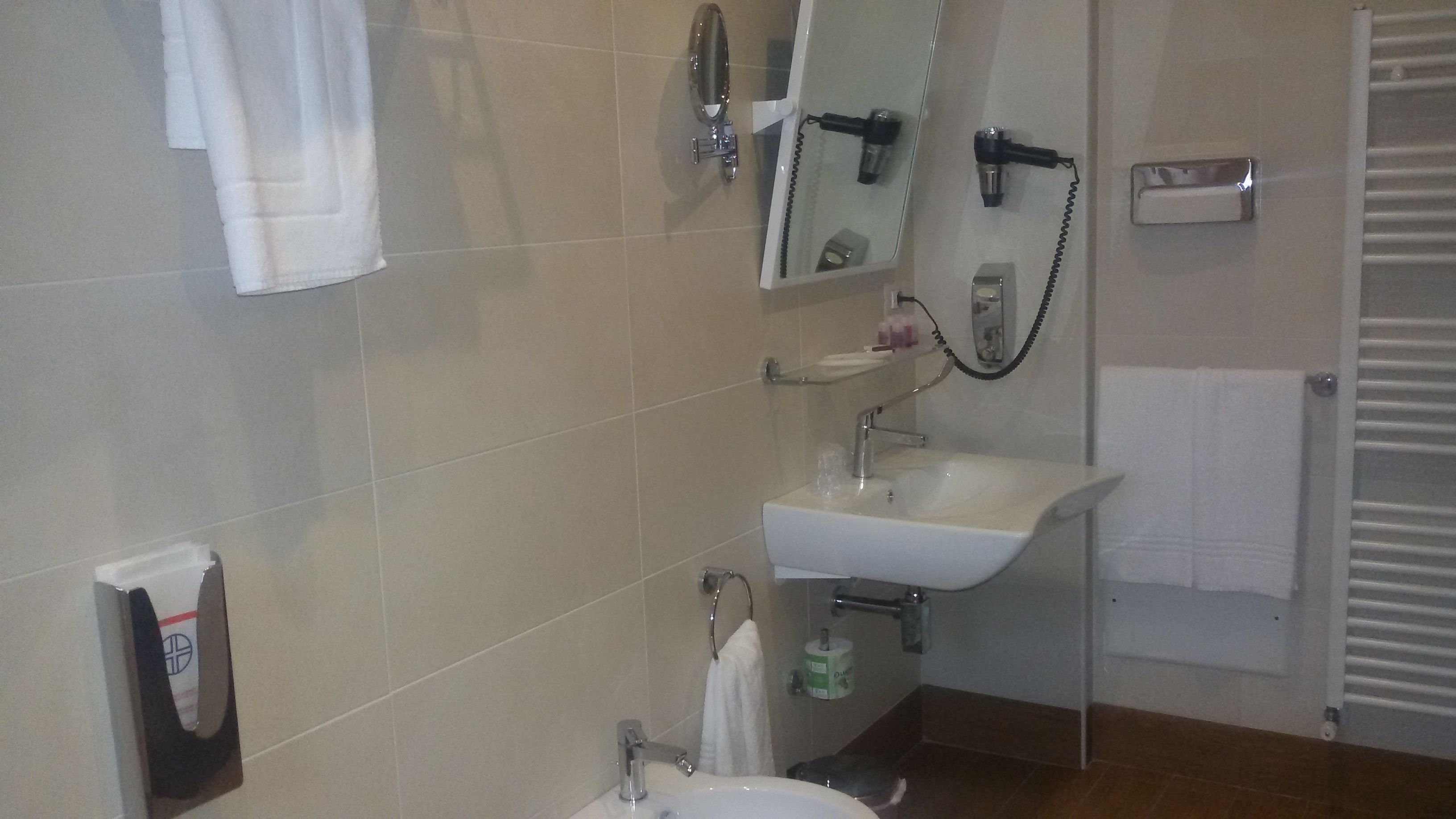 A bathroom with a sink, mirror, towel rack, and a shower area.
