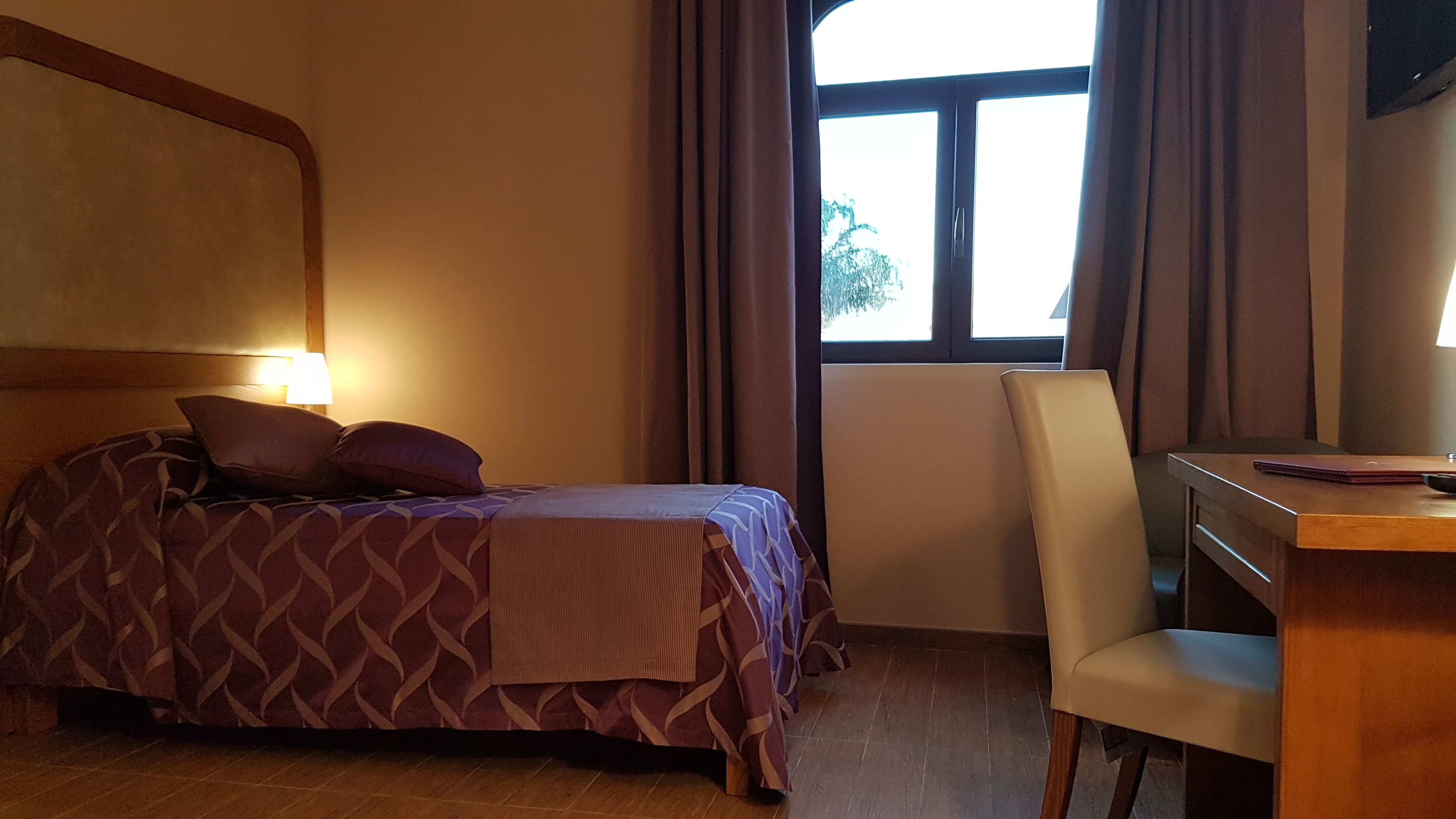 A hotel room with a bed, a desk, and a chair.