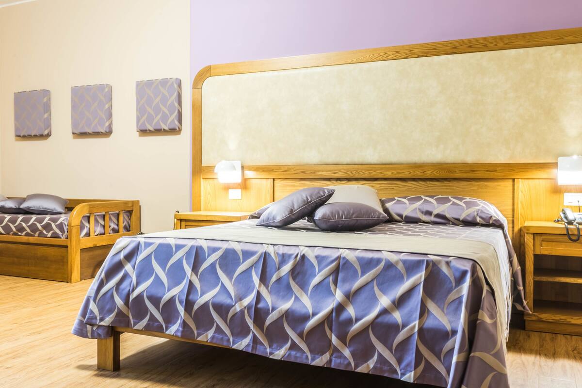 Ein Hotelzimmer mit einem großen Bett, zwei Nachttischen und drei Wandlampen.