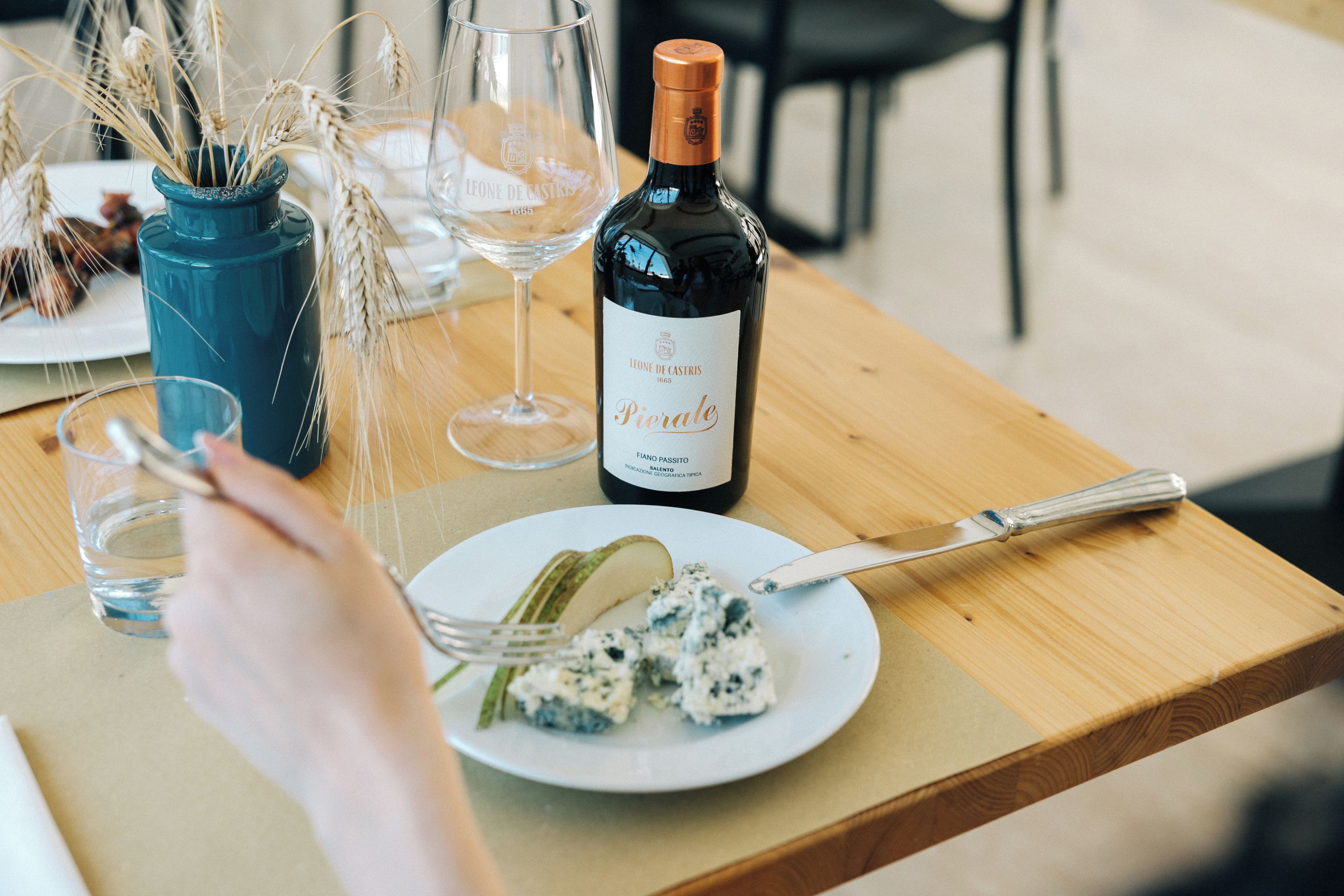 A dining table with a bottle of wine, glasses, and a plate of food.