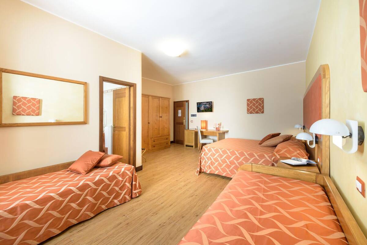 Ein Hotelzimmer mit zwei Betten, einem Schreibtisch, einem Stuhl und einem Kleiderschrank.