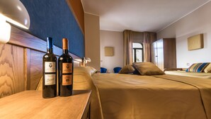 A hotel room with two beds, a wooden headboard, and two bottles of wine on the nightstand. - Leone De Castris Wine Hotel (Salice Salentino)