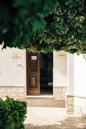 A reception area with a wooden door, a sign for 'Villa Donna Lisa,' and a sign indicating 'Reception.' - Leone De Castris Wine Hotel (Salice Salentino)