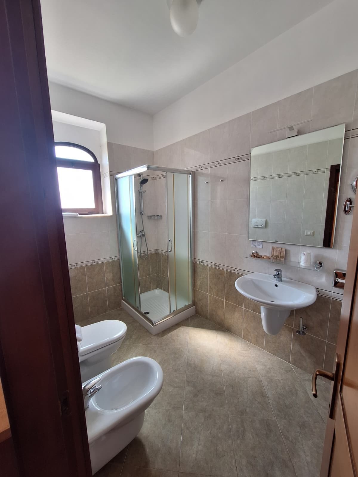 A bathroom with a glass-enclosed shower, a sink, and a toilet.