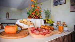A breakfast table with various food items, including cheese, meats, fruits, and a drink. - Carlo's Hotel (Castagneto Carducci)