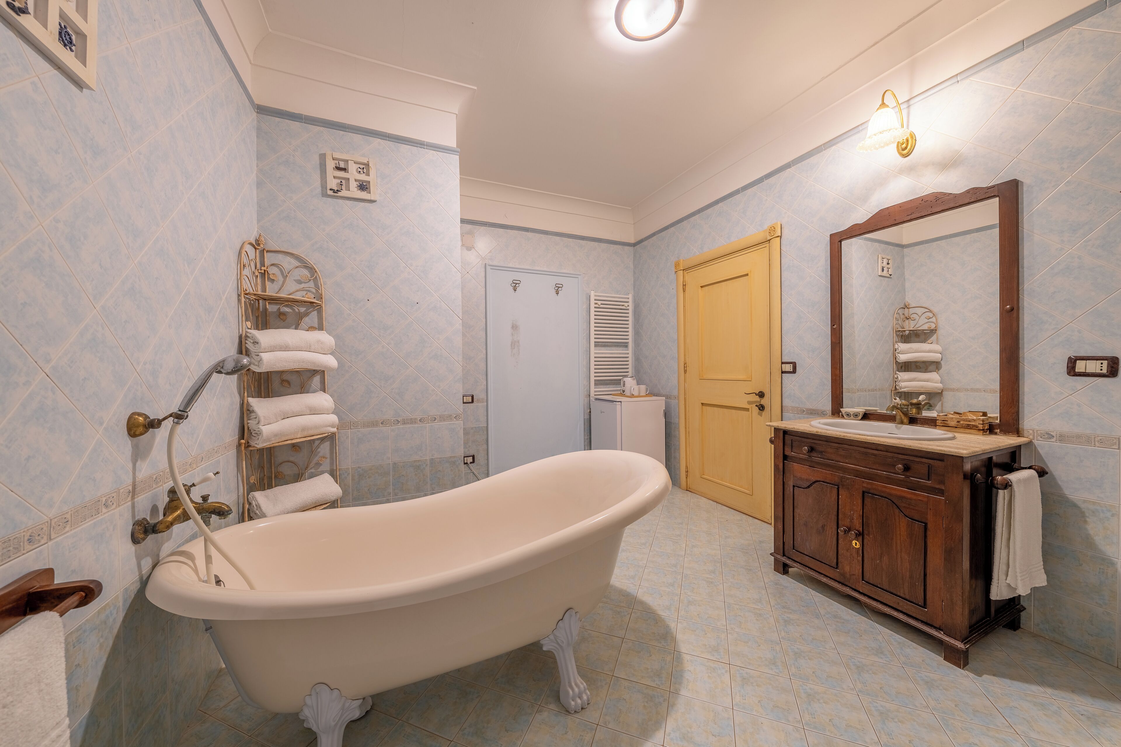 A bathroom with a freestanding bathtub, a wooden vanity with a mirror, and a towel rack.