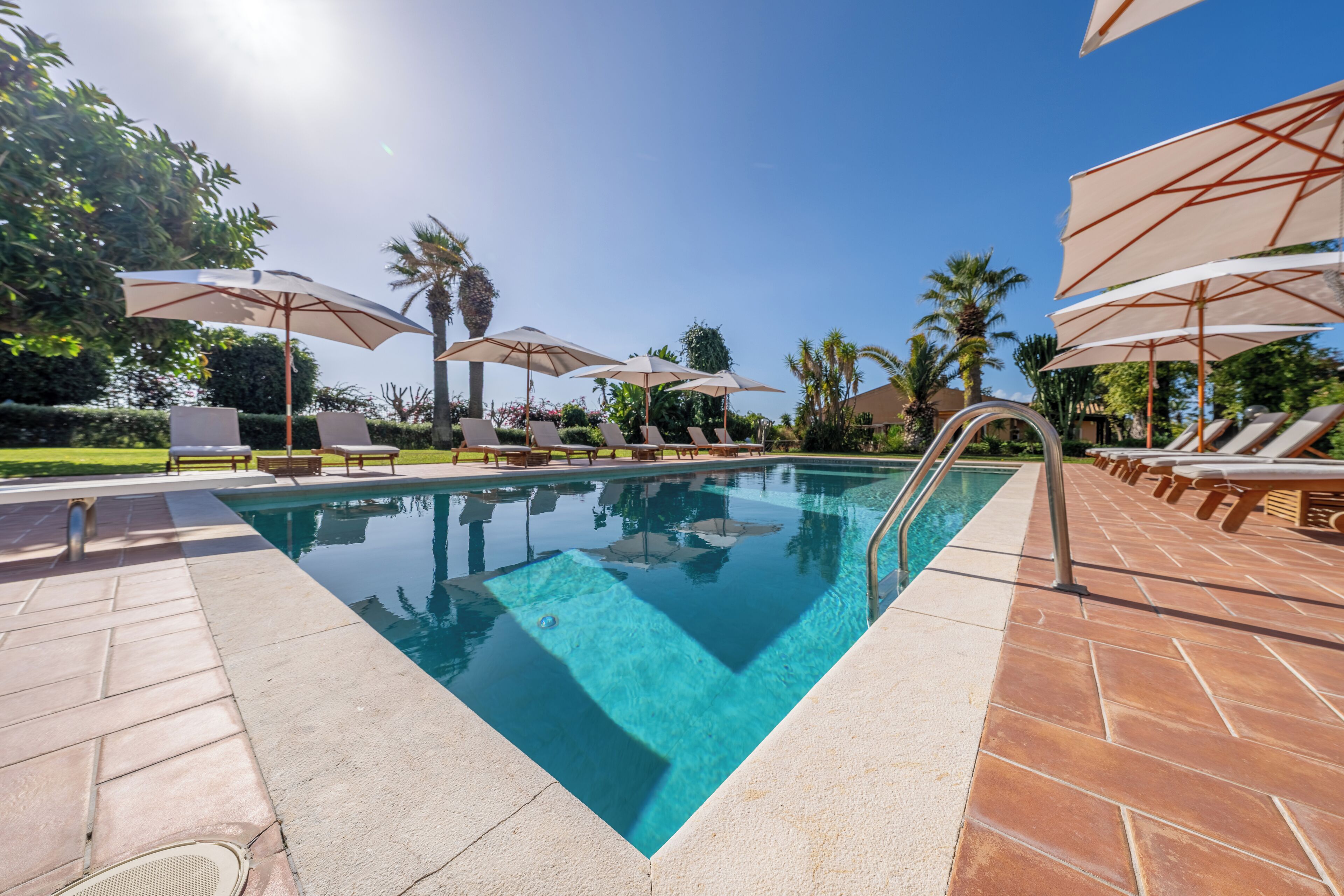 A pool area with lounge chairs and umbrellas.