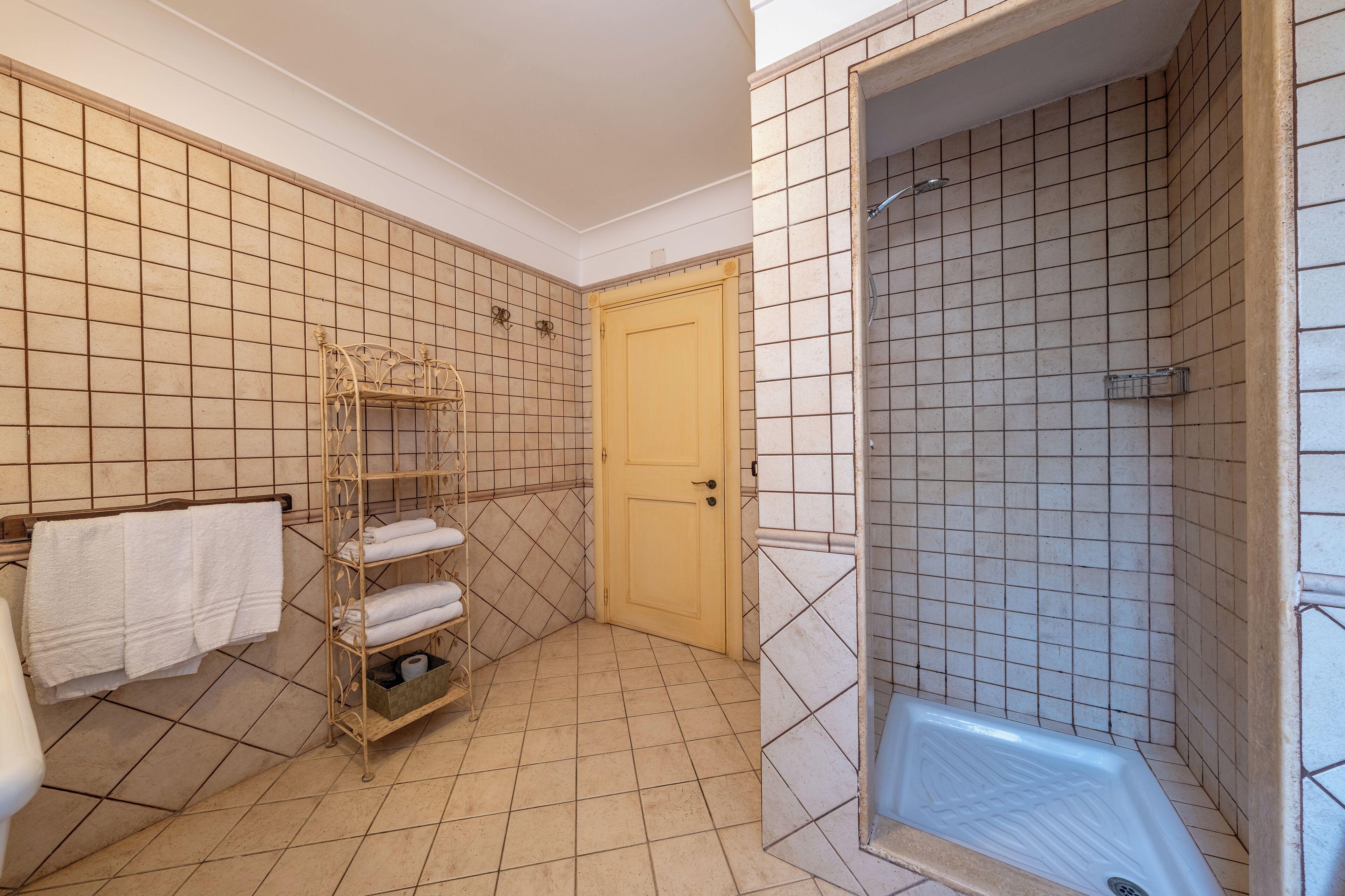 Un baño con ducha, un perchero con toallas y una puerta.
