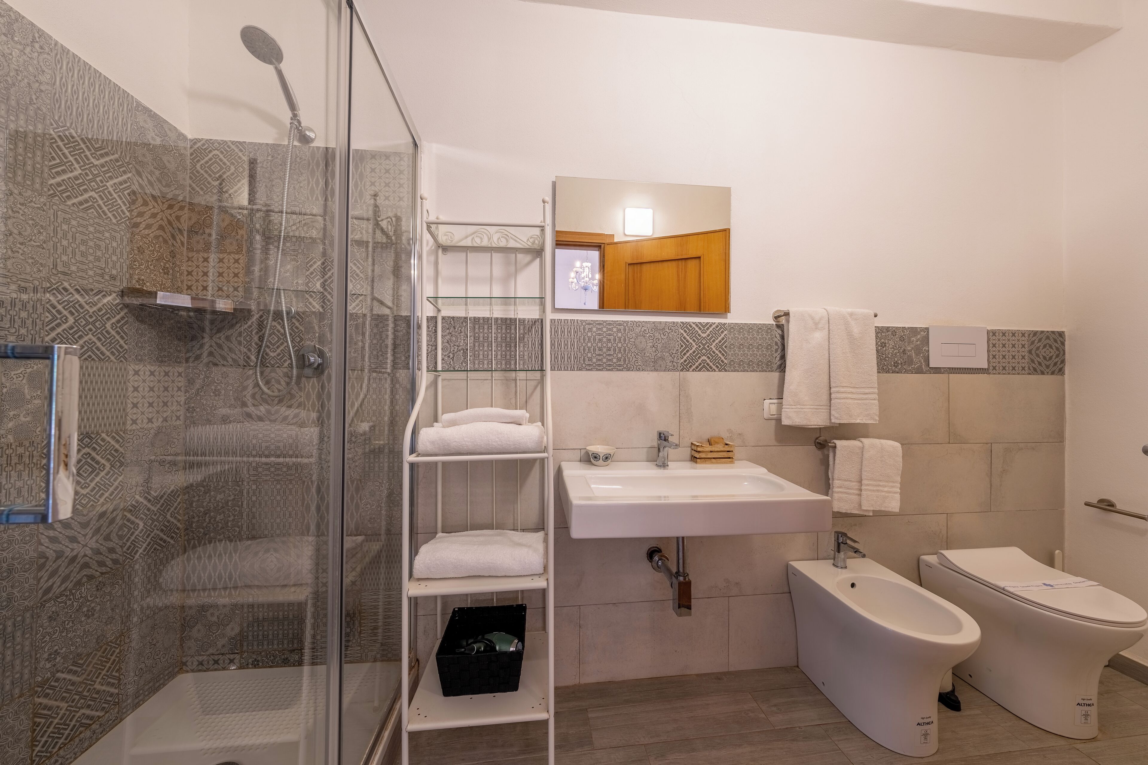 Een moderne badkamer met een glazen douchecabine, een wit wastafelmeubel, een toilet en een spiegel boven de wastafel.