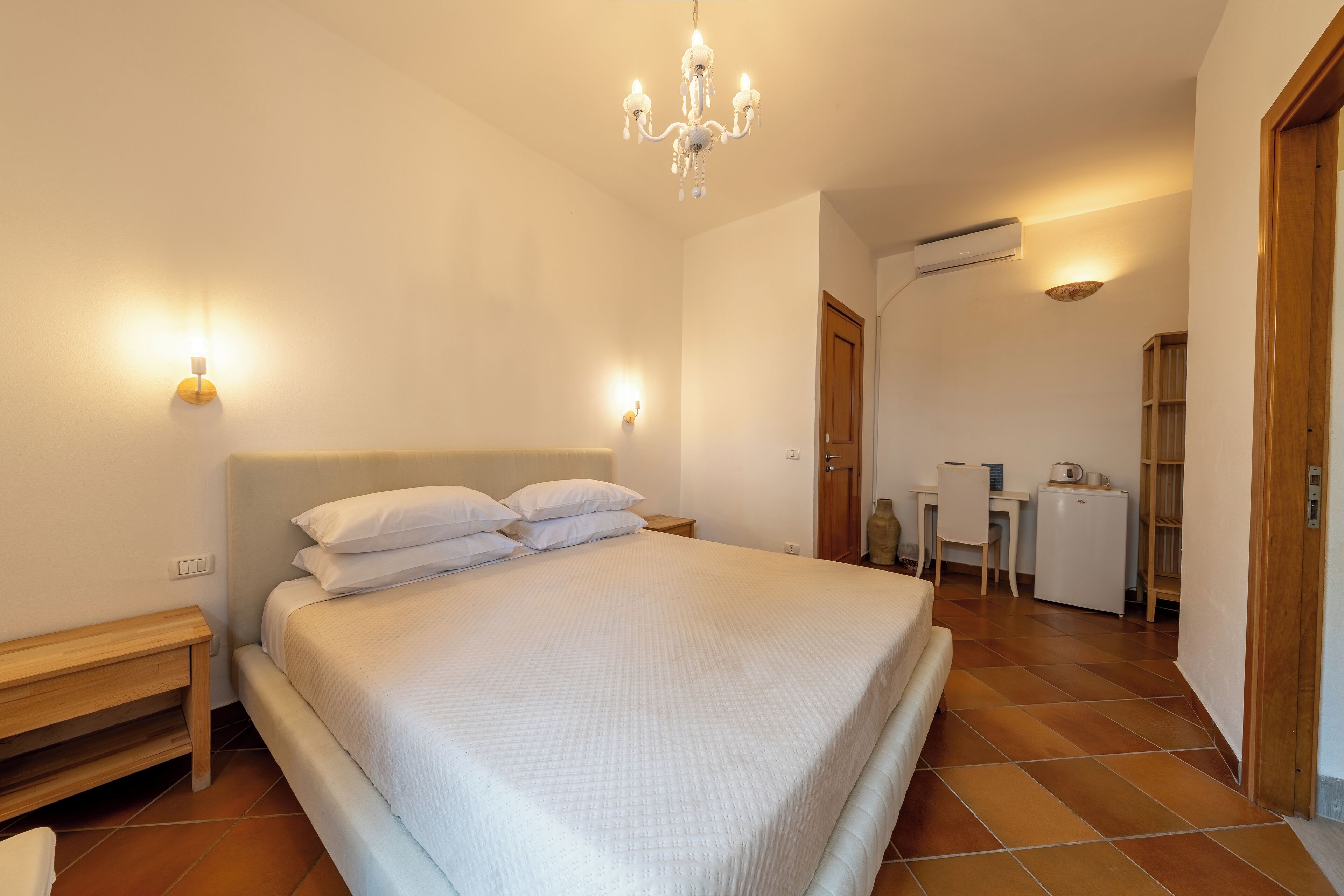 A bedroom with a large bed, bedside tables, a desk, and a chair.