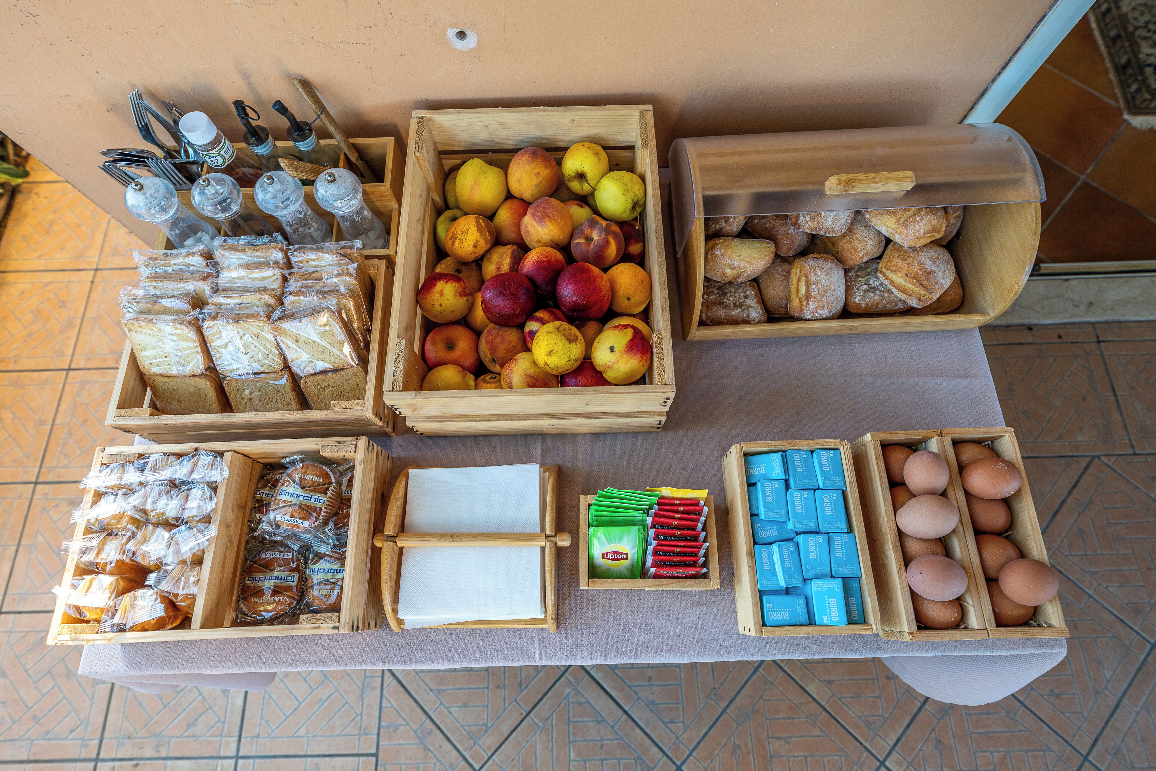 A table with various food items including bread, pastries, apples, and eggs.
