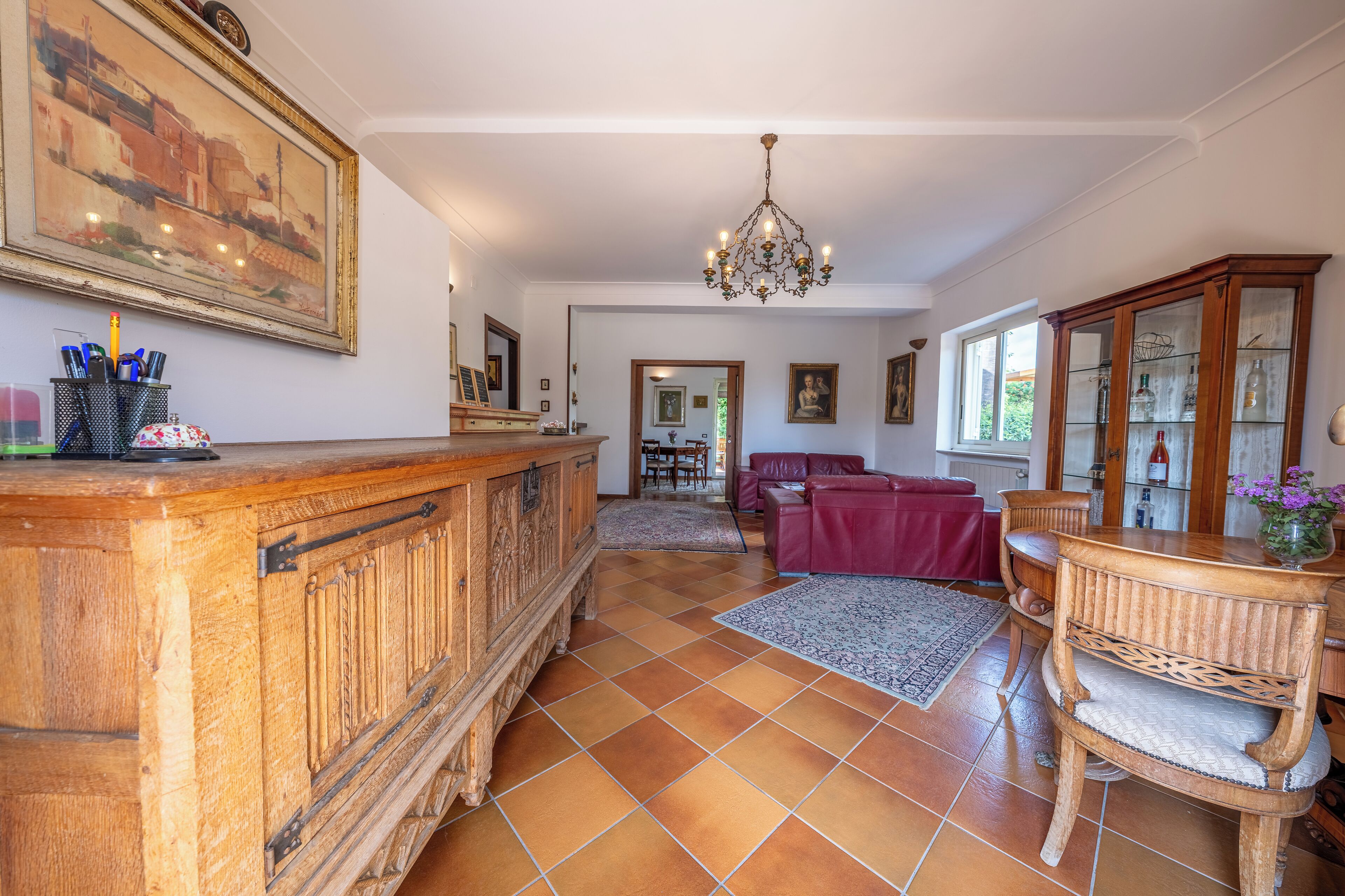Un vaste espace de vie comprenant un bar en bois, un lustre et un ensemble de meubles de salle à manger.
