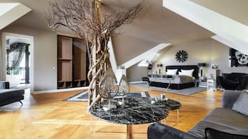 Un loft espacioso con techo alto, una mesa central de mármol negro, un sofá moderno y una escultura decorativa de un árbol.